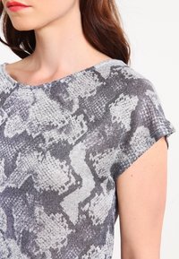 Short-sleeve gray and white top with a textured snake print design. The fabric appears lightweight and knit, with a loose fit and round neckline.
