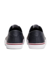 Laivaston siniset nahkaiset tennarit pyöreällä muotoilulla, valko-puna-raitoitetulla pohjalla ja pehmustetulla kauluksella. Siistit ompeleet korostavat rakennetta.