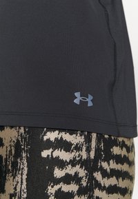 Černé sportovní tričko s krátkými rukávy a bočními švy, se modrým logem Under Armour. Nosené přes vzorované černé a zlaté legíny.