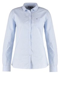 Jasnoniebieska, w pionowe paski, koszula z długim rękawem wykonana z bawełny, z kołnierzykiem zapinanym na guziki, kieszenią z przodu oraz białymi guzikami. Teksturowana tkanina z delikatnym połyskiem.