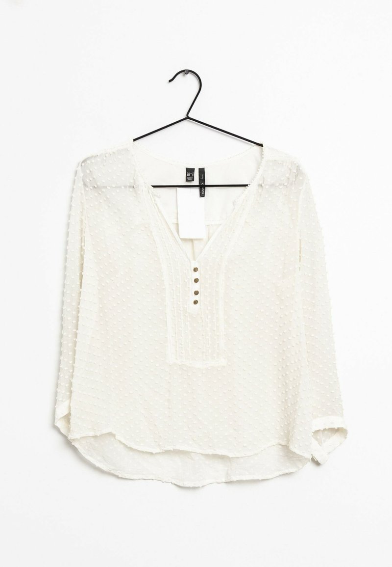 Camicia bianca con pois testurizzati, scollatura a V e placket a tre bottoni. Maniche lunghe con polsini leggermente arrotolati. Tessuto leggero e trasparente.