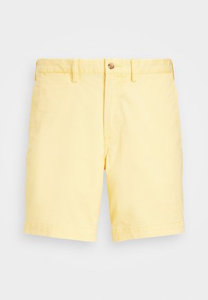 Gaiši dzelteni kokvilnas šorti ar pogu aizdari, kas pieejami ar plakanu priekšpusi, sānu kabatām un taisnu piegriezumu virs ceļa.