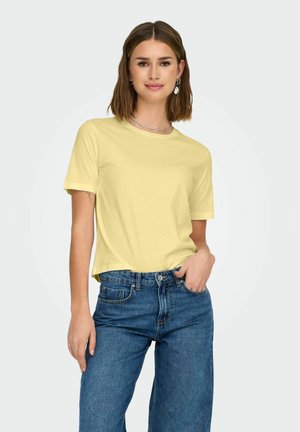 T-shirt di cotone giallo con maniche corte e scollatura rotonda, abbinata a jeans in denim blu a vita alta. Design semplice, vestibilità comoda.