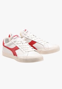 Sneaker bianche con accenti rossi e logo, dotate di tomaia in pelle liscia, chiusura a lacci e suola in gomma con grip testurizzato.