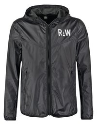 Zwarte lichtgewicht jas met capuchon, een rits aan de voorkant, ritssluitingen aan de zijkanten en een wit "RAW"-logo op de borst.