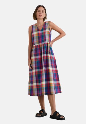 Vestido de estampado floral con escote en V, diseño sin mangas y cintura fruncida. Los colores incluyen púrpura, rojo, verde y amarillo. Se lleva con sandalias negras.