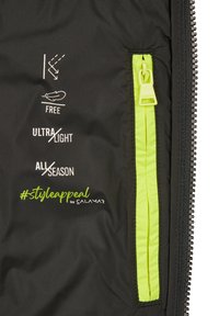 Sort jakke inderside med en lys grøn lynlås-lomme. Funktioner ikoner, der angiver vandtæt, letvægts og helårsbrug, med logo.