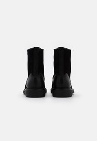 Botas negras que combinan ante y cuero, con un acabado suave, paneles laterales elásticos y una suela baja y duradera.