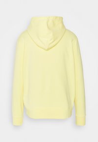 Sweat à capuche jaune clair vu de dos, avec manches longues et poignets ainsi qu'ourlet côtelés, sur un fond uni.