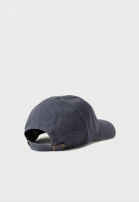 Σκούφος από βαμβάκι σκούρου μπλε χρώματος με κυρτή γείσο, ρυθμιζόμενο λουράκι στο πίσω μέρος και ραμμένες τρύπες αερισμού στην κορυφή.