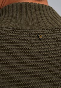 Maglione lavorato a maglia verde oliva con colletto a coste, corpo testurizzato con motivo a rete e un piccolo tag metallico con marchio sul retro.