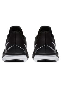 Černé sportovní boty s elegantním designem, s texturovaným svrškem a bílými akcenty. Na patě je nápis "JUST DO IT".