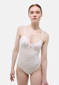 Bodysuit en dentelle blanche avec des motifs floraux, des bretelles réglables, un décolleté en V profond et un détail en trou de serrure à l'avant. Texture lisse et transparente.