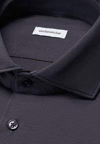 Camicia colletto grigio scuro con una trama di stoffa liscia, dotata di chiusura a bottoni e un'etichetta con scritto "seidensticker" vicino al colletto.