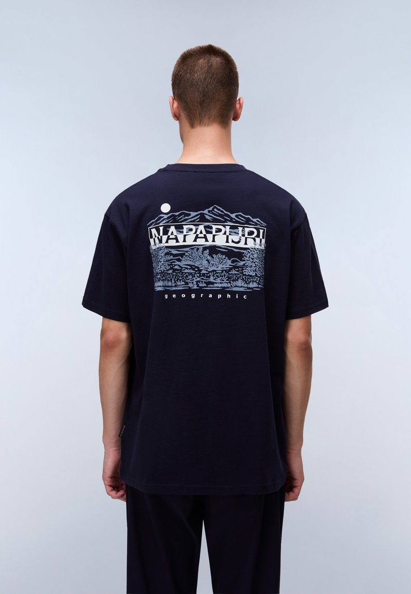 Navy blue cotton t-shirt featuring a graphic print of mountains and trees on the back, with "NAPAPIJRI" text above. Short sleeves, relaxed fit.