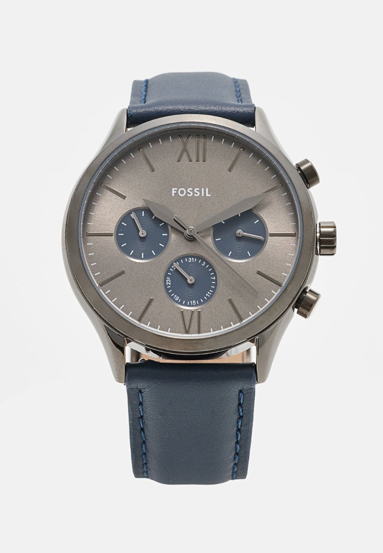 Montre Fossil avec un cadran métallique gris, trois sous-cadrans, bracelet en cuir bleu et accents en ton argent, avec des indices en chiffres romains.