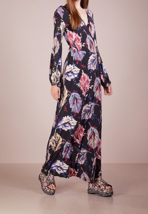 Kvinde iført en langærmet, gulvlang blomsterkjole med en indpakket V-hals og platform sandaler med blomster mønster.