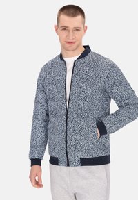 Giacca bomber blu navy con motivo astratto bianco, bordi a coste sulle maniche e l'orlo, chiusura frontale con zip, progettata con due tasche laterali.