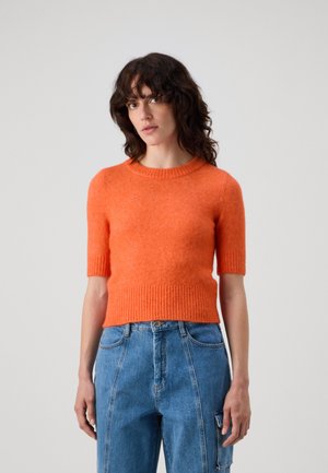 Oranger kurzärmeliger Strickpullover mit Rundhalsausschnitt und geripptem Saum, kombiniert mit hellblauen hochtaillierten Jeans.