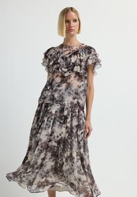 Abito trasparente con motivo floreale, maniche arricciate e gonna plissettata; i colori includono crema, taupe e marrone. Tessuto leggero e strutturato.