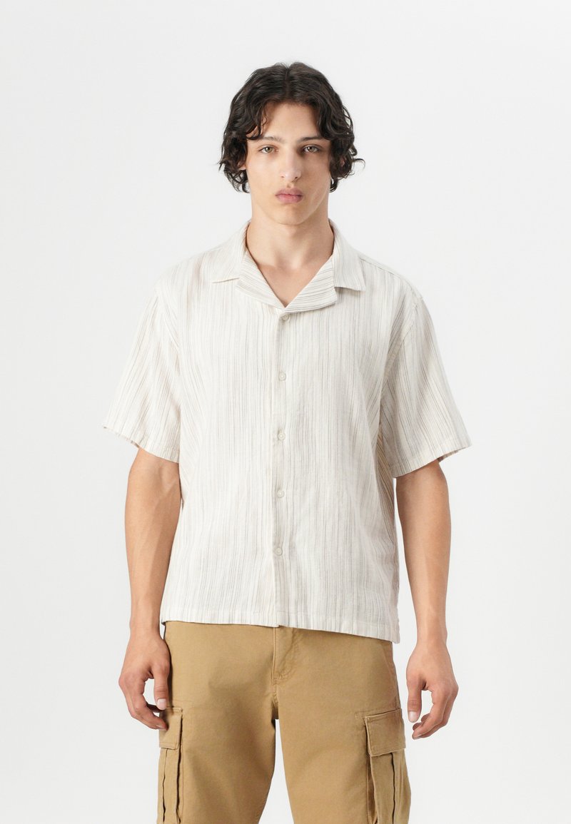 Korte mouw button-up shirt in lichtbeige met dunne verticale strepen, voorzien van een spread collar en een relaxte pasvorm. De stof lijkt textuur te hebben.