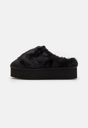 Chaussons à enfiler en fausse fourrure noire avec une semelle plateforme noire épaisse ; texture douce et design arrondi, adaptés pour une utilisation en intérieur.