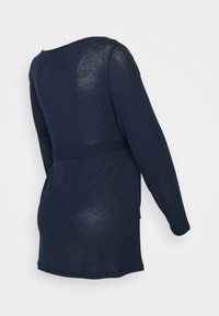 Camisa de manga longa azul marinho com decote redondo, textura suave, detalhe de cintura cingida e corte solto, ideal para sobreposições.
