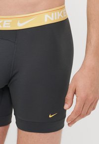 Herrarnas Nike boxershorts i svart med en gul logotyp och midja. Fitted design med slätt, elastiskt tyg och inga synliga sömmar.