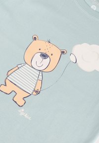 Light blue t-shirt featuring a cartoon bear with an orange-brown body, striped shirt, and a balloon-shaped cloud, detailed with simple lines.