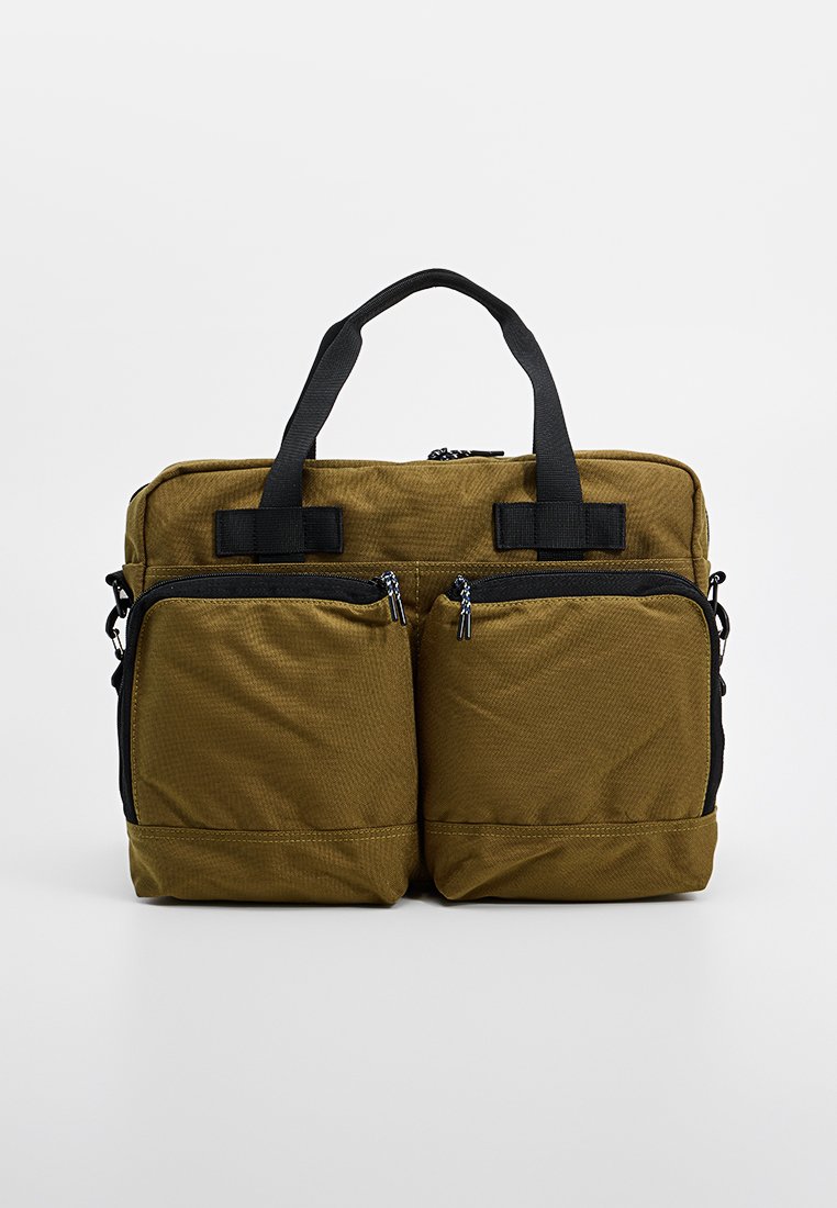 Bolsa de tela verde oliva con dos bolsillos frontales con cremallera, asas dobles y forma rectangular, con una superficie texturada y acentos en negro.