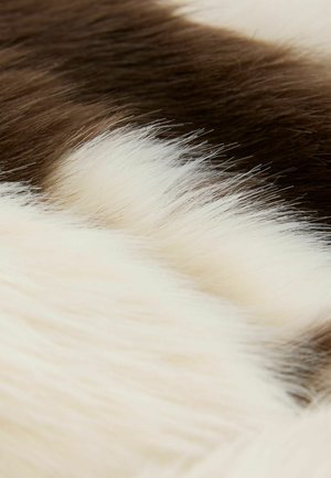 Sztuczne futro w odcieniach brązu i kremu, charakteryzujące się gęstą, miękką fakturą o różnej długości włosa, tworzącą naturalny, warstwowy wygląd.