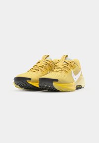 Des chaussures de sport jaunes avec une tige en mesh, un bout renforcé, des accents blancs et une semelle extérieure en caoutchouc noir texturé pour une meilleure adhérence.