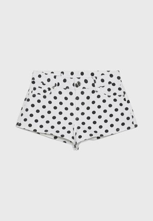 Hvide denimshorts med sorte polkaprikker, foran knap og lynlås samt lommer foran og bagpå, vist på en ensfarvet baggrund.