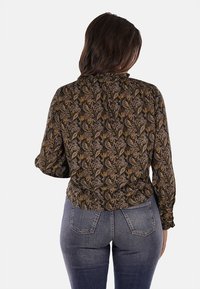 Maglietta nera con motivo paisley in tonalità di oro e viola, tessuto semi-trasparente, maniche lunghe, colletto arricciato e vita elastica.