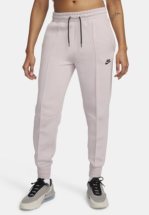 Lichtroze sweatpants met een trekkoord in de taille, zijzakken en een zwart Nike-logo. Gemaakt van zacht materiaal met een gladde textuur.