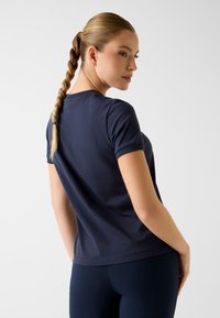 Granatowy bawełniany t-shirt z krótkim rękawem, okrągłym dekoltem i lekkim rozciągnięciem. Gładka faktura bez widocznych wzorów czy akcentów.