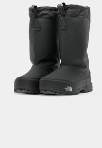 Botas impermeables negras con un exterior liso y resistente al agua, cierre de cordón en la parte superior y suela robusta para tracción.
