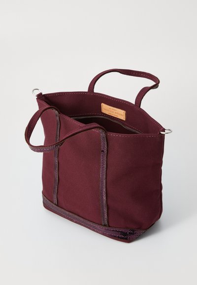 Maroon canvas tote bag with two short handles, reinforced stitching, and a zip closure. Features a leather label inside.