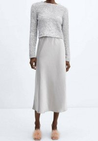 Maglione: tessuto argento morbido, design cropped, maniche lunghe. Gonna: materiale grigio chiaro liscio, lunghezza caviglia. Calzature: ciabatte morbide rosa fluffy.
