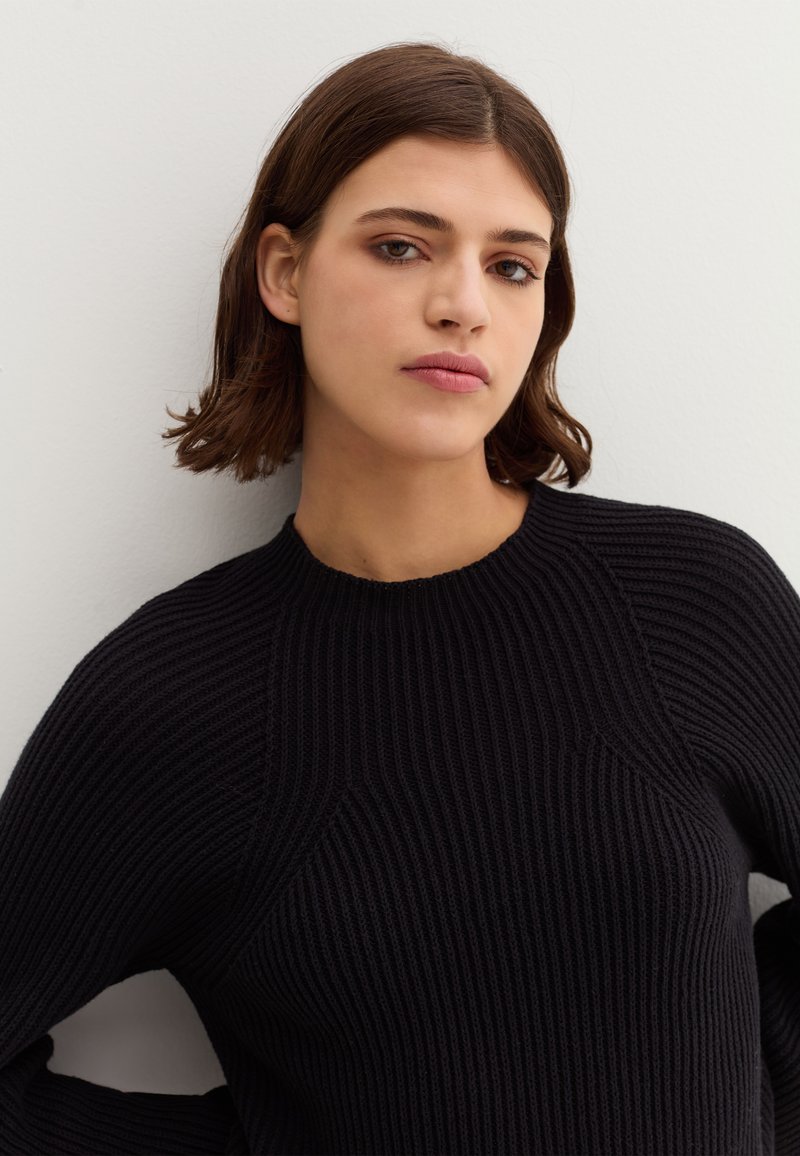 Schwarzer gerippter Strickpullover mit runde Ausschnitt und strukturierter Stoff. Verfügt über subtile Details an den Schultern und Seiten.