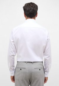 Witte blouse met lange mouwen en een spread collar, met knopenmanchetten en een gladde textuur, gecombineerd met grijze maatwerk broek met achterzakken.