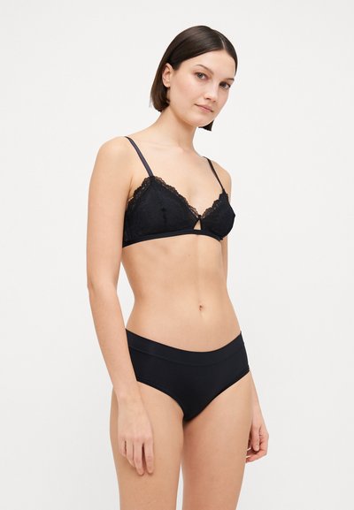 Black lace bralette with triangular cups, thin straps, and a keyhole detail. Paired with black hipster underwear, smooth fabric, and a simple design.