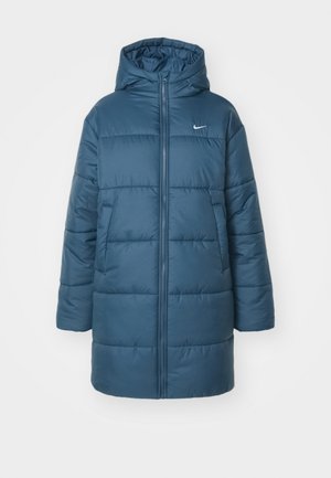 Töltött dzseki türkiz színben, elől cipzárral, nagy kapucnival és oldalsó zsebekkel. Keresztvarrás és egy kis logó található a mellkason.