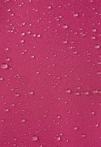 Wasserabweisender Stoff in lebhaftem Pink, mit zahlreichen kleinen, klaren Tropfen, die über eine strukturierte Oberfläche verteilt sind.