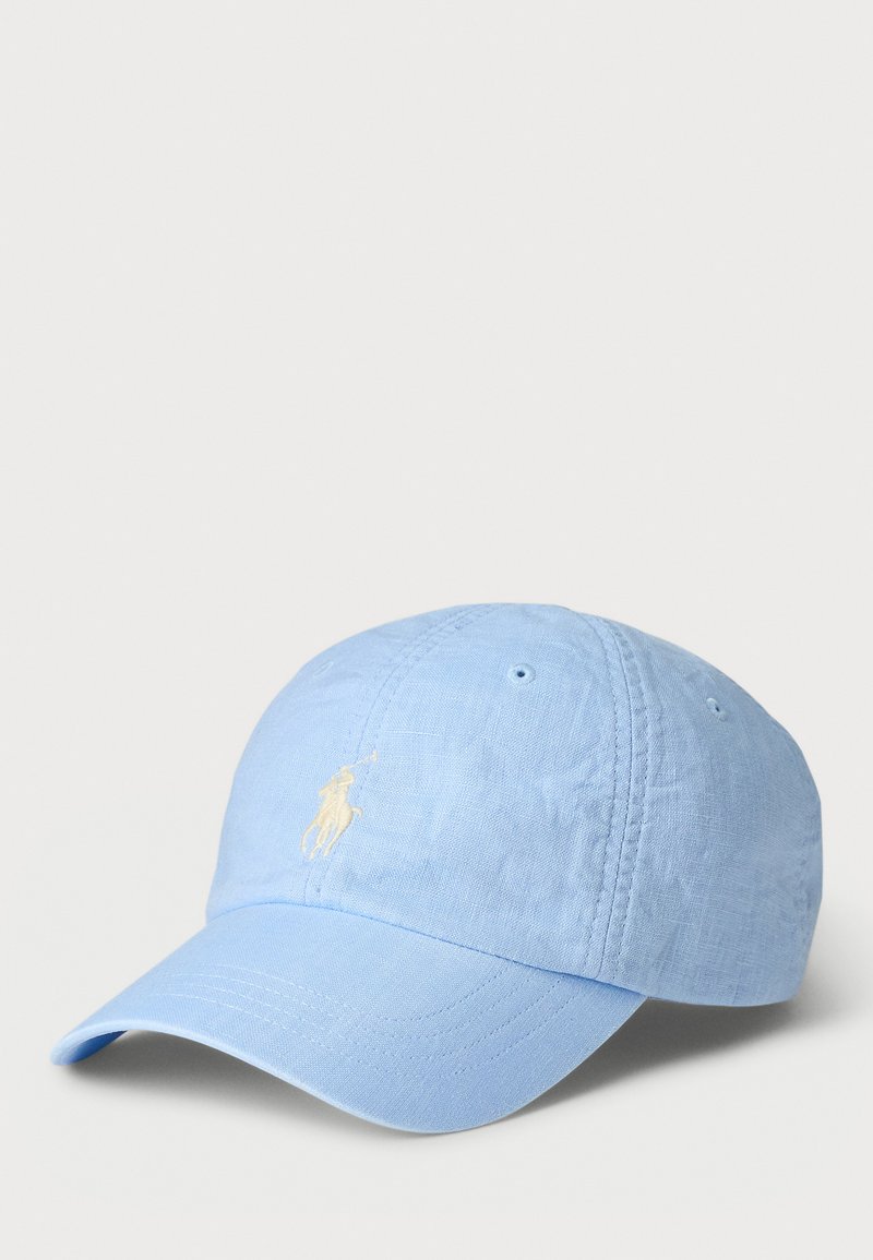 Lyseblå bomullsbasketcap med buet skjerm og brodert logo i krem, med ventilasjonsøyer på toppen.