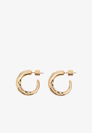 Pár malých, lesklých zlatých zakrivených kruhových náušníc s uzáverom na zapínanie na bielom pozadí.