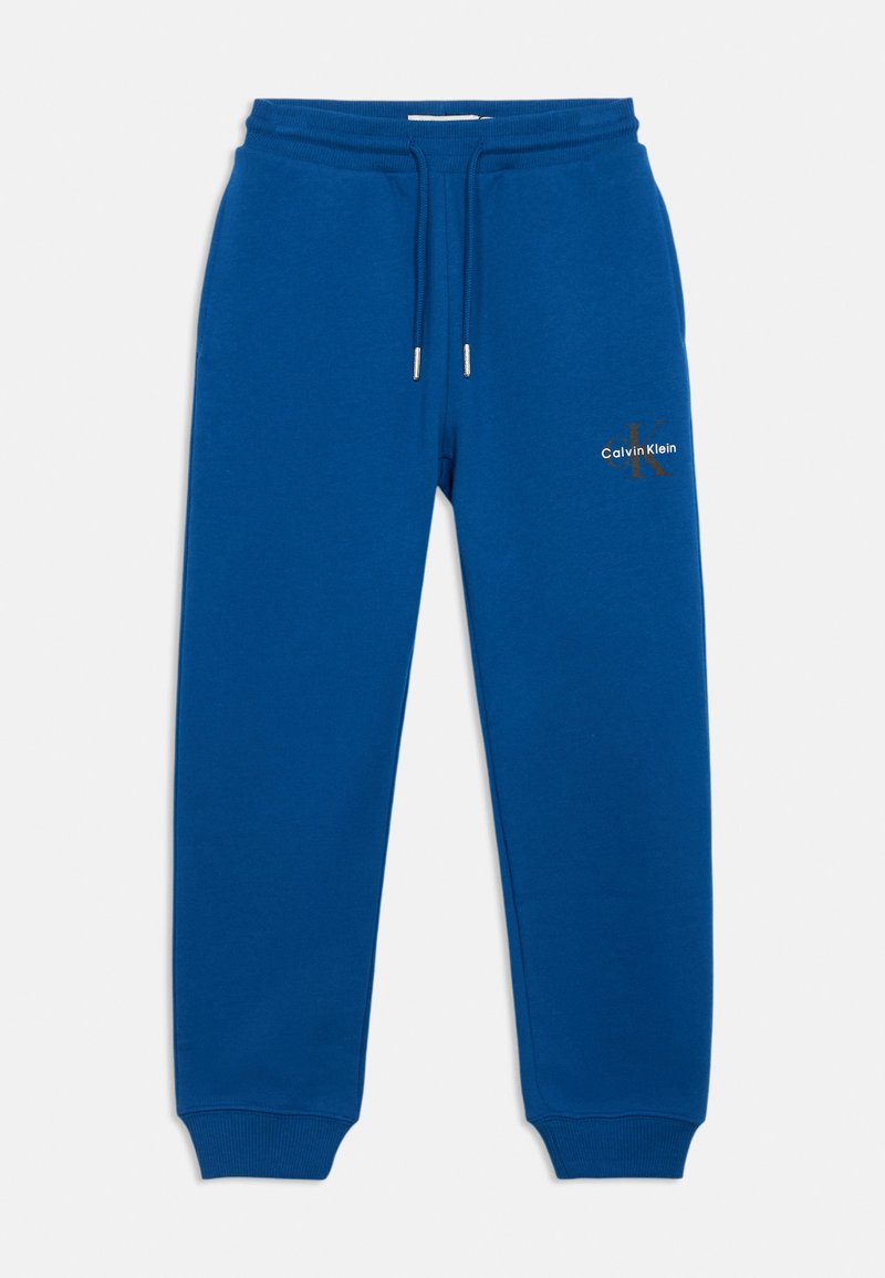 Kék melegítő nadrág puha textúrával, rugalmas derékpánttal és zsinórral. A bal combon található egy kis "Calvin Klein" logó.