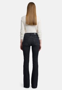 Jeans évasés noirs taille haute avec une texture denim classique, cinq poches et un détail de couture bleu moyen à l'arrière.