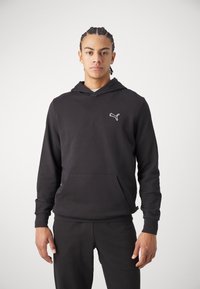 Felpa nera in cotone con tasca a marsupio, dotata di un logo Puma bianco sul lato sinistro del petto e polsini e orlo a costine.