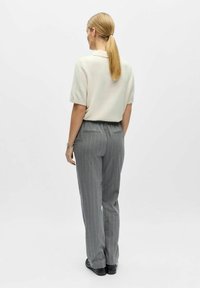 Kreemikas lühikeste varrukatega kudum, mille külge on sobitatud hallid triibulised püksid, millel on elastne vöökoht ja kaks tagataskut. Sile tekstuur, istuv lõige.